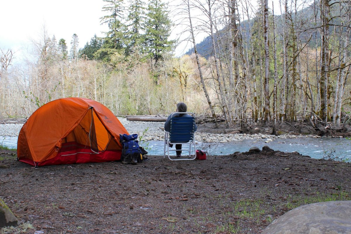 Man camping by a river with camping gear