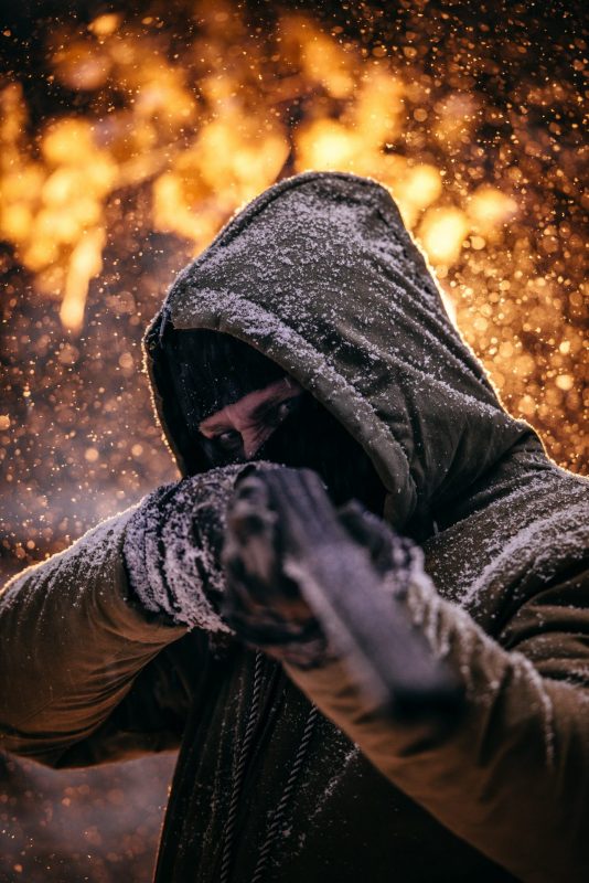 person wearing gray hoodie holding hunting rifle