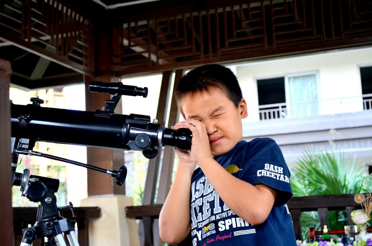 kid looking into a telescope